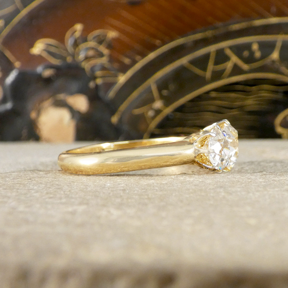 Gold ring with a diamond on a textured surface with decorative background