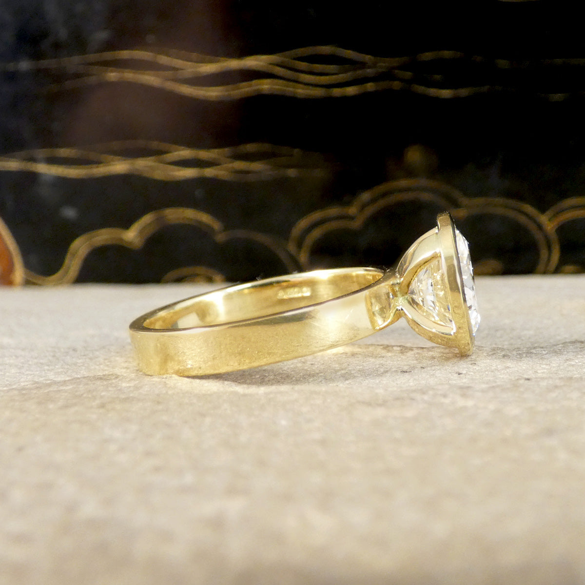 A diamond solitaire ring in a rub over bezel setting in 18ct yellow gold with exposed sides to allow more light to pass through the diamond