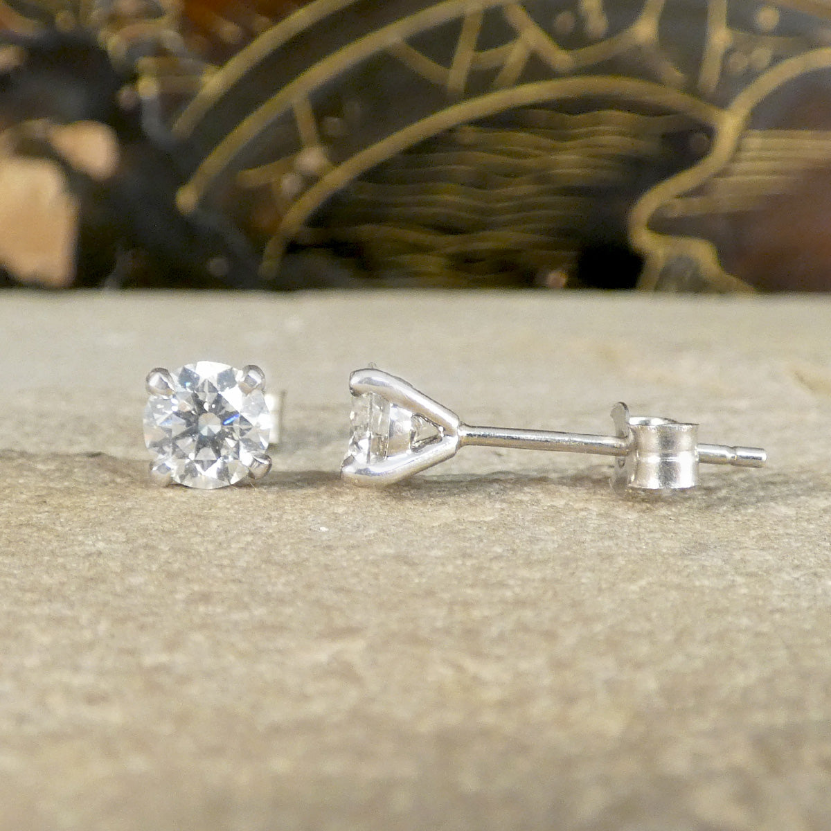 A pair of four claws diamond stud earrings shown from the front and side.