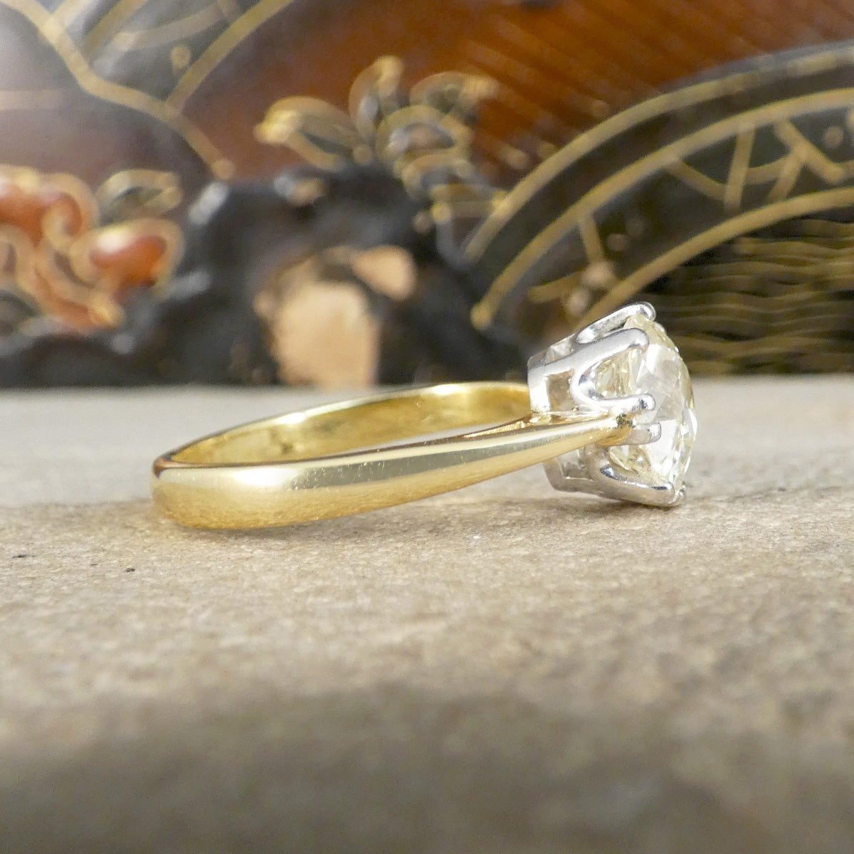 Gold ring with a diamond on a textured surface with a decorative background