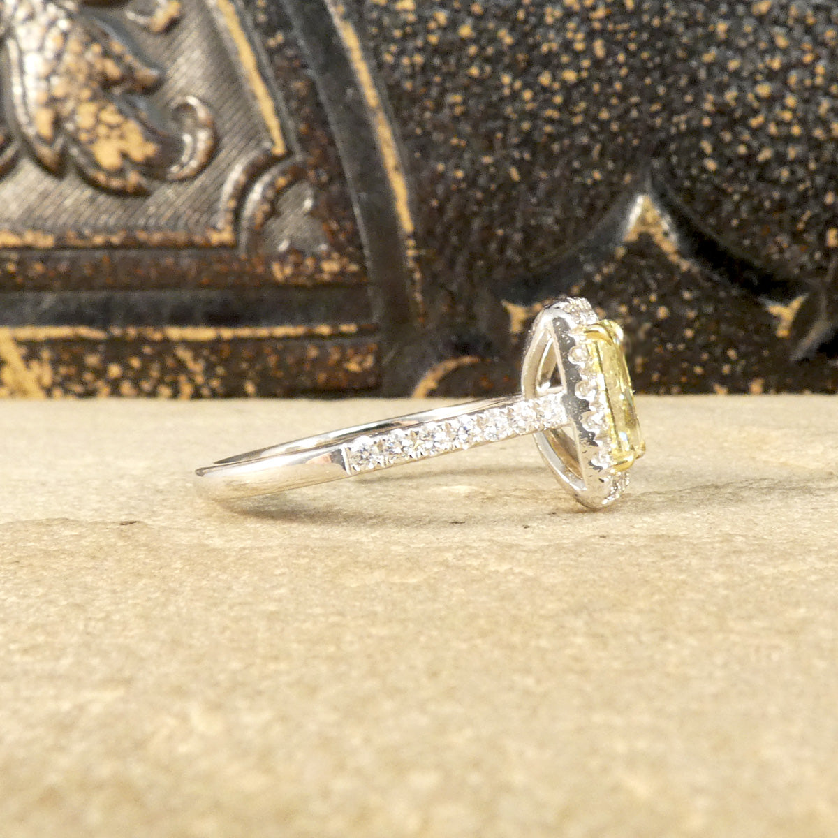 Side profile of Natural Yellow Radiant Cut Diamond with GIA grading in a four claw setting. Surrounded by a halo of bright white Diamonds and Diamond set shoulders in 18ct White Gold. Perfect engagement ring.