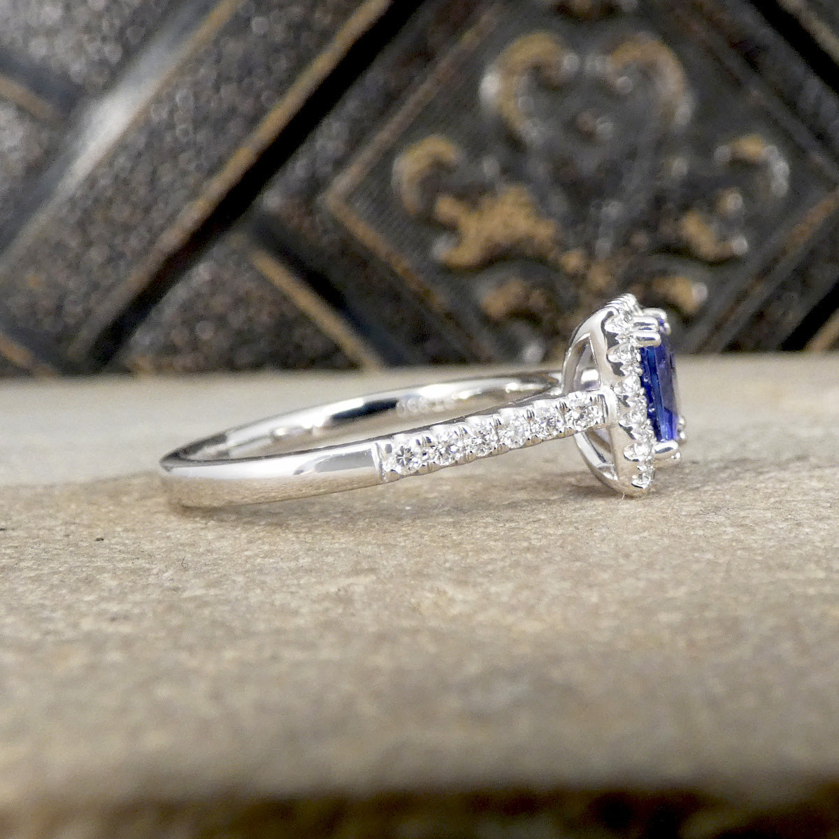 Platinum ring with a blue gemstone and diamond accents on a textured surface.