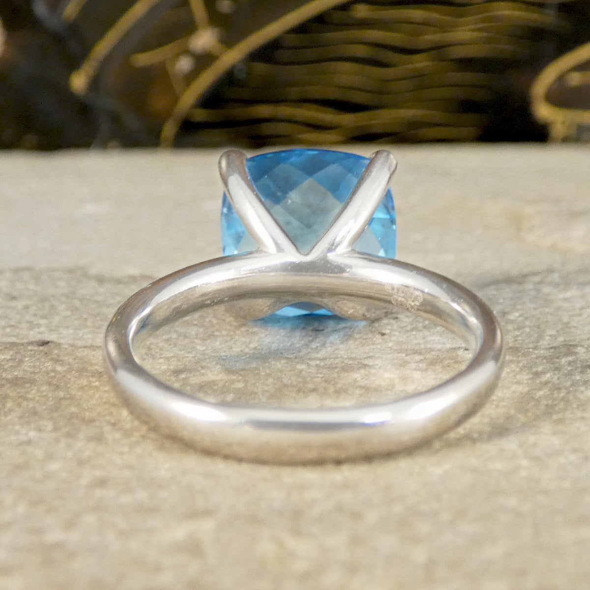 White Gold ring with a blue topaz gemstone on a wooden surface