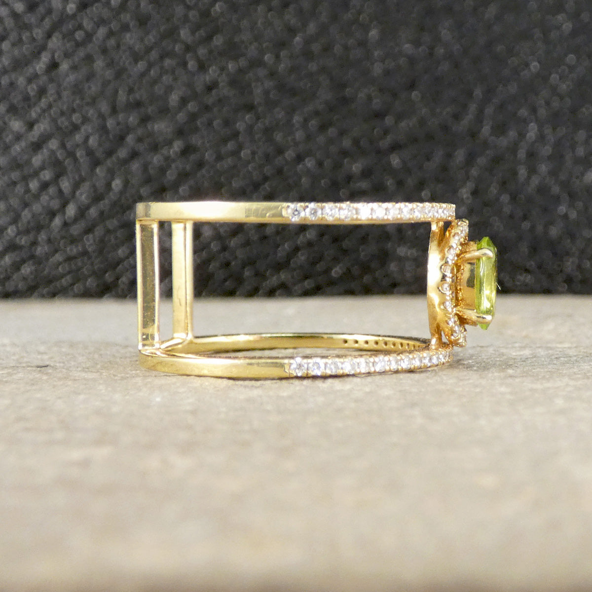 Gold ring with a green gemstone on a textured surface
