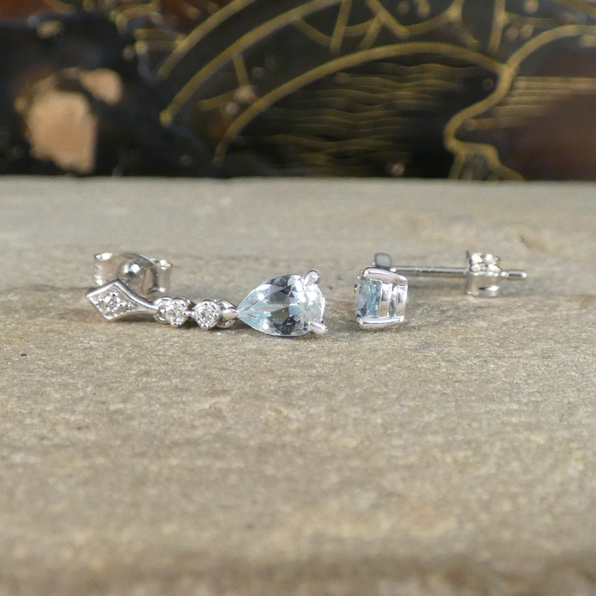 Pair of 18ct white gold earrings with gemstones on a textured surface