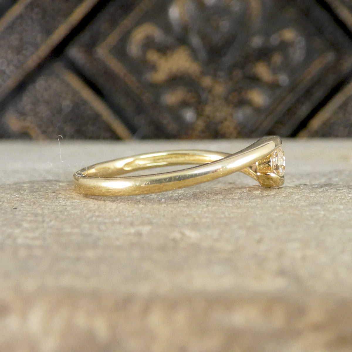 Gold ring with a diamond on a textured surface with a blurred background