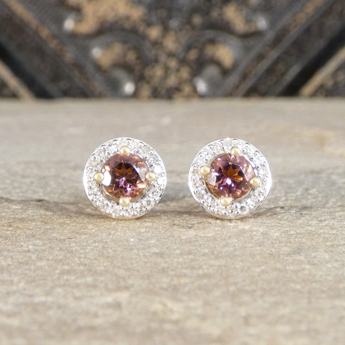 Pair of round earrings with gemstones on a textured surface