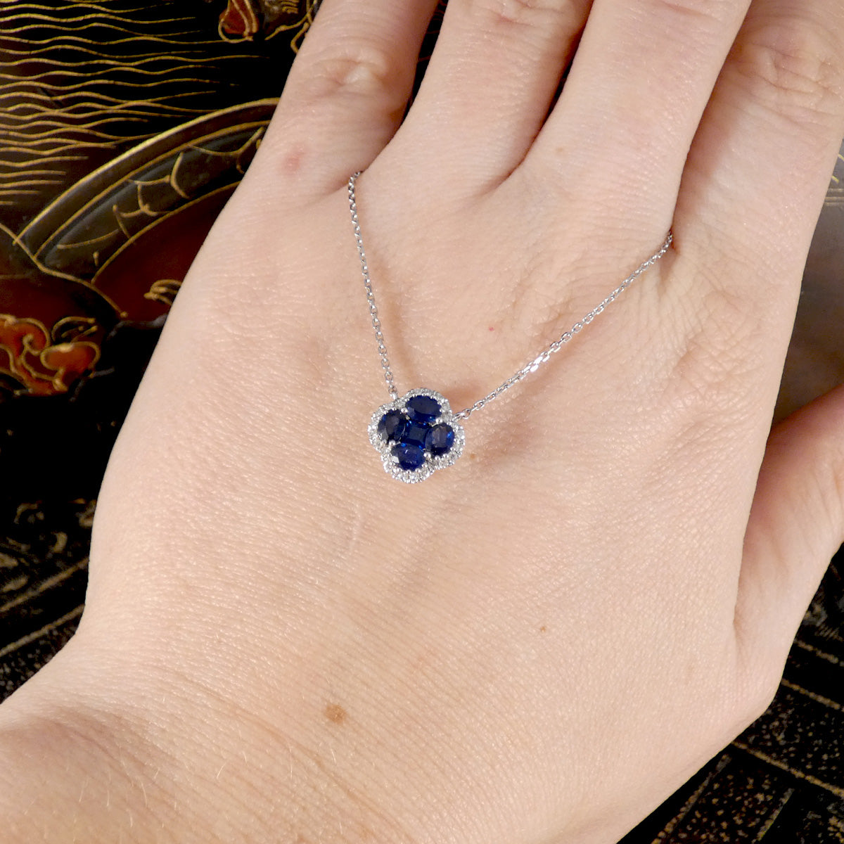 a blue sapphire necklace shown on a hans