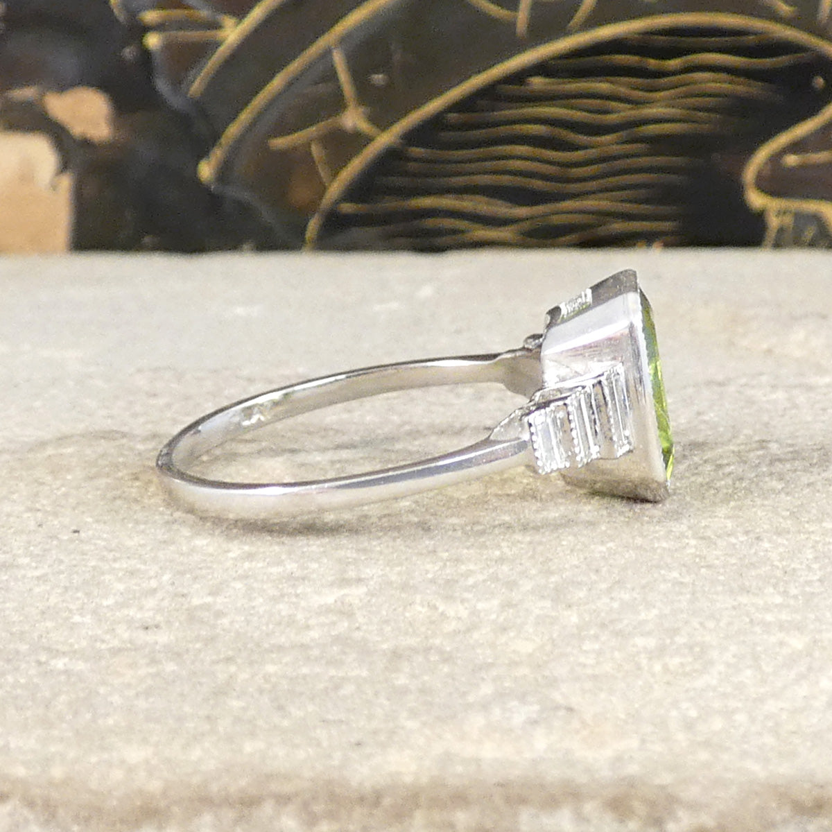 Side view of Art Deco Inspired Peridot and Baguette Cut Diamond Staged Shoulders in Platinum.