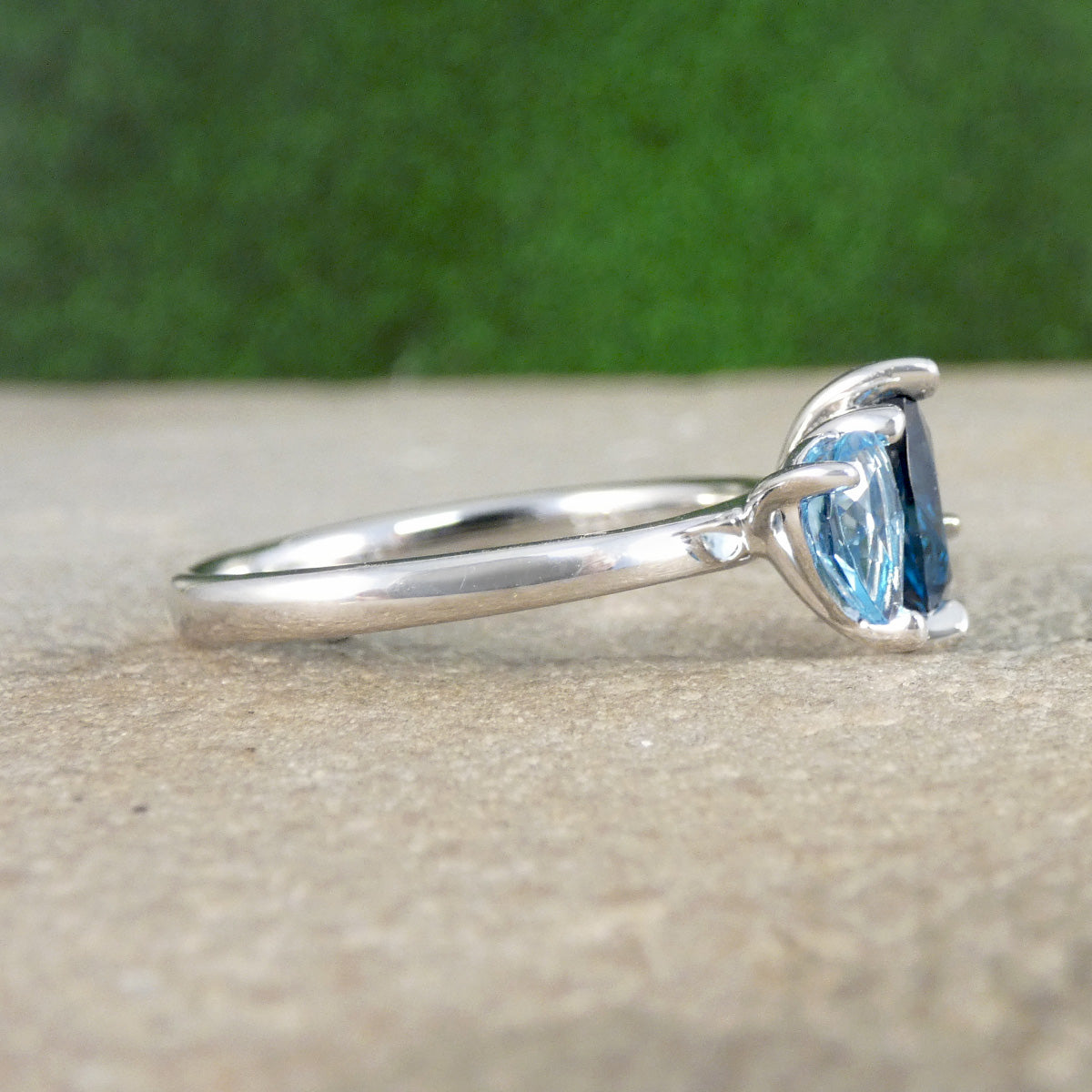 Silver ring with a blue gemstone on a textured surface with a green blurred background