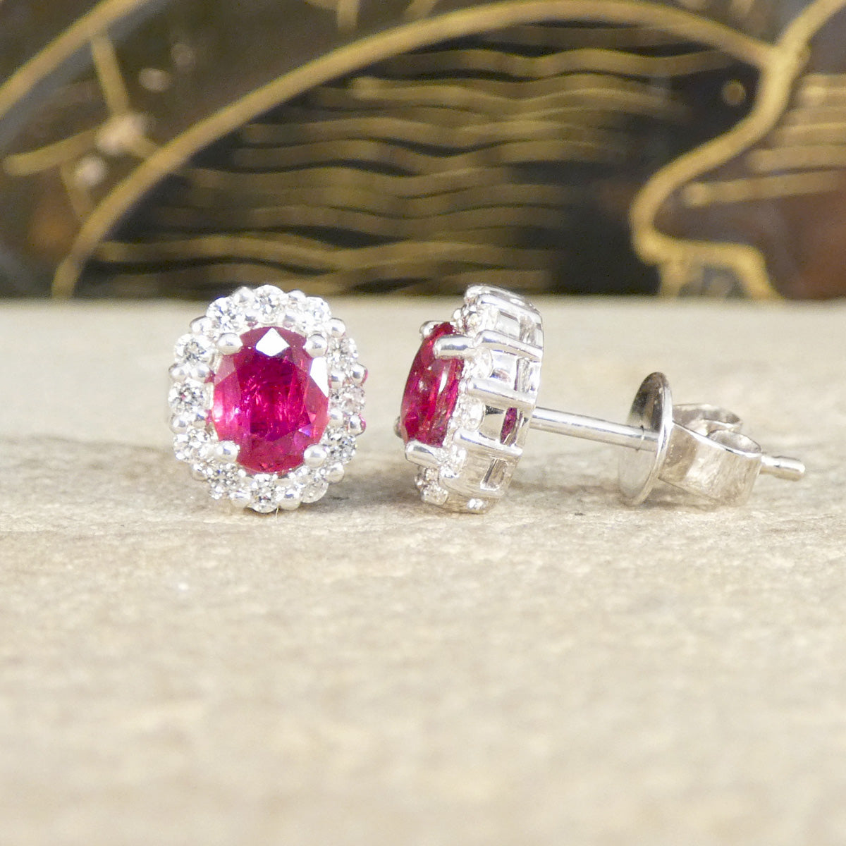 Pair of earrings with red gemstones and silver settings on a beige surface.