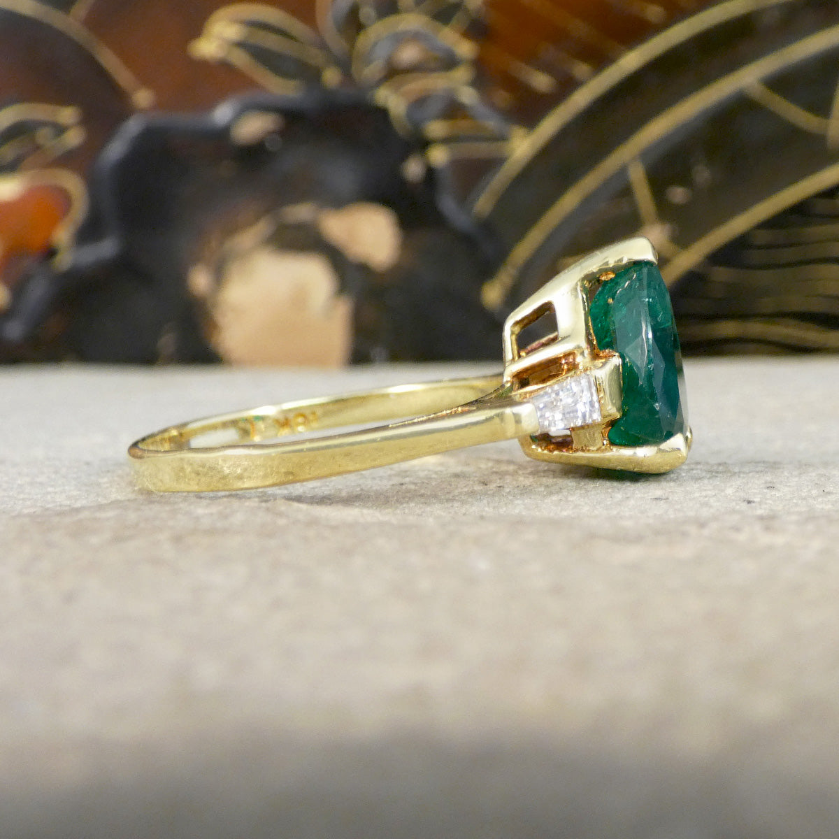Gold ring with a green gemstone on a neutral background