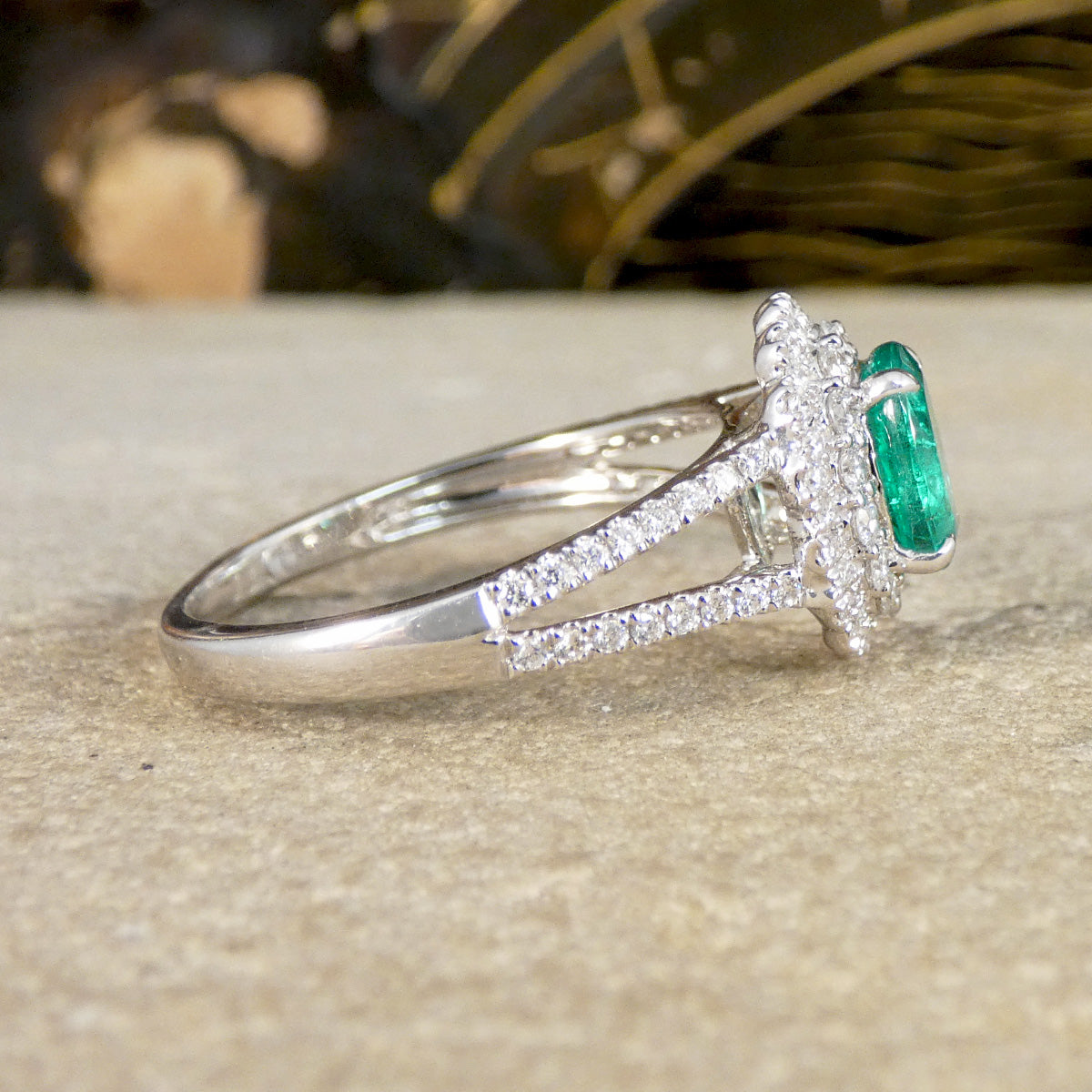 Emerald and diamond cluster ring shown from the side.