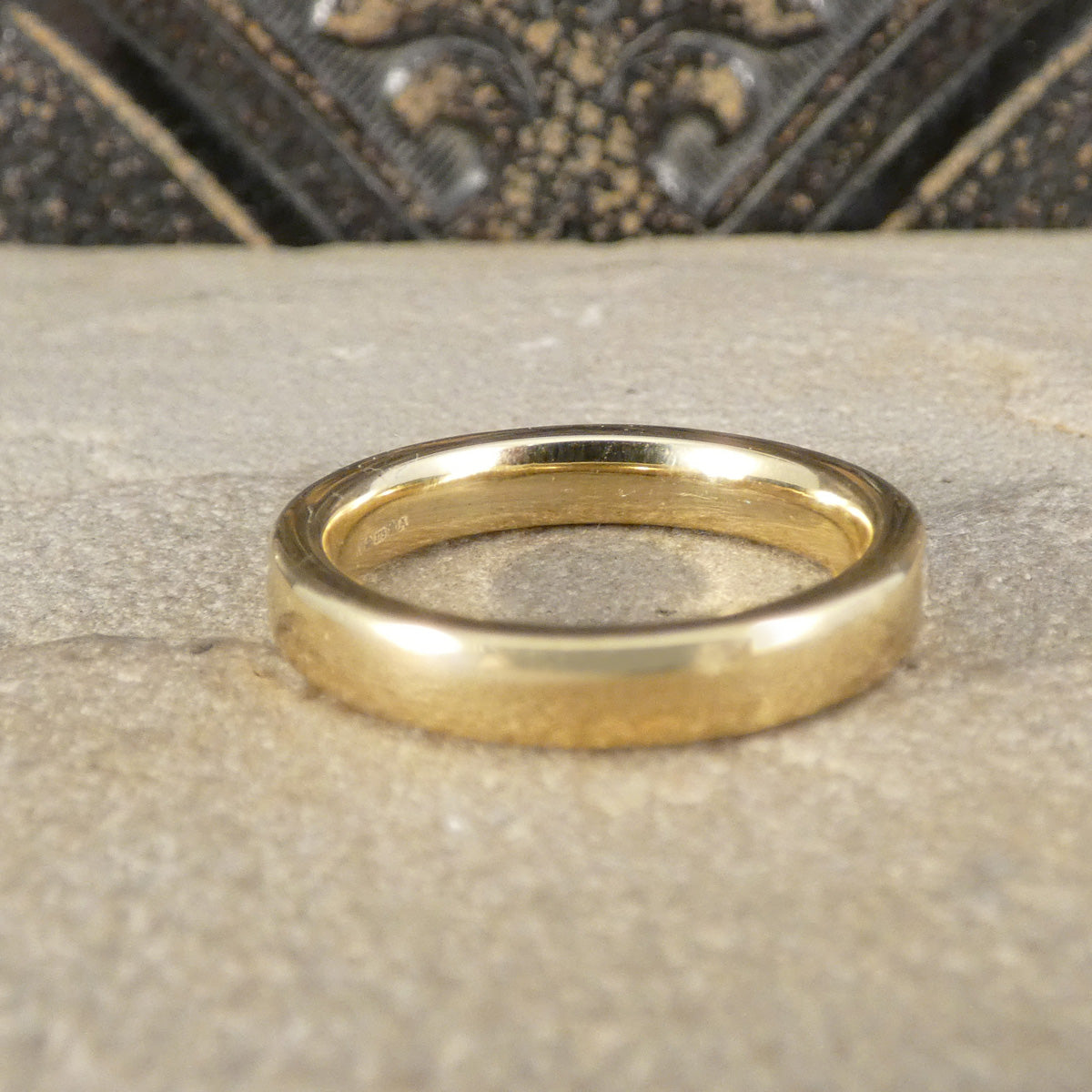 Gold ring on a textured surface with a decorative background