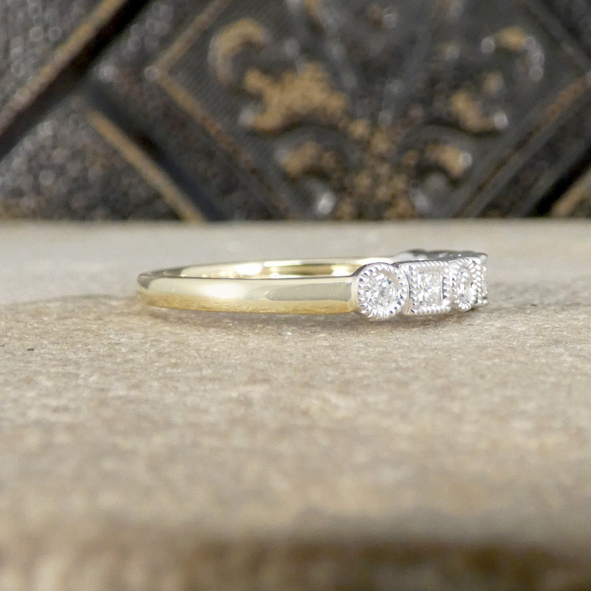 Gold ring with diamonds on a textured surface