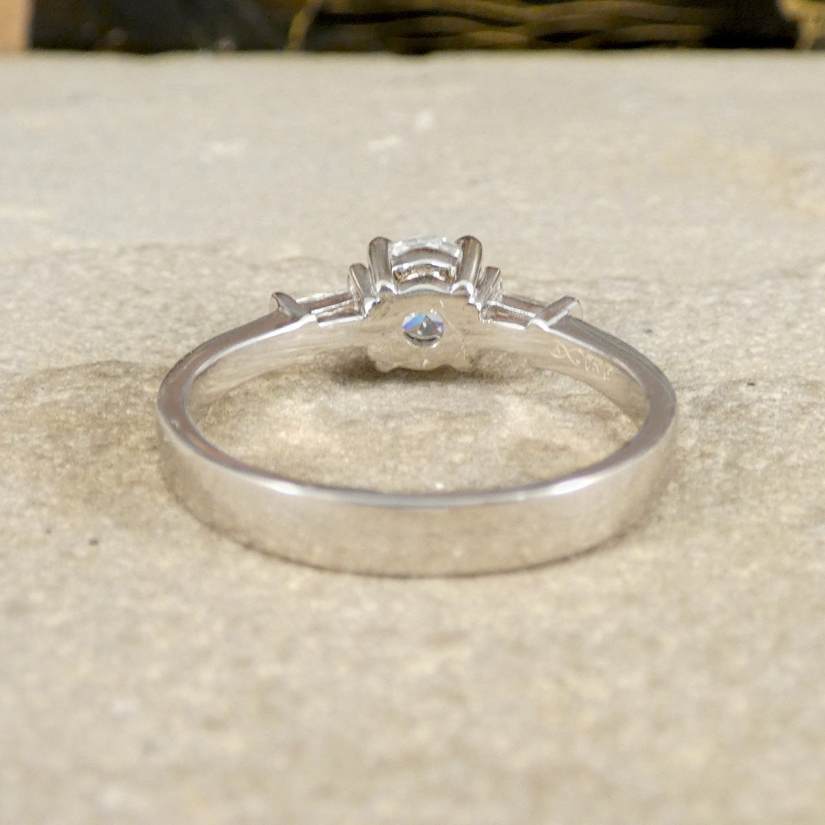 Silver ring with a diamond on a textured beige surface