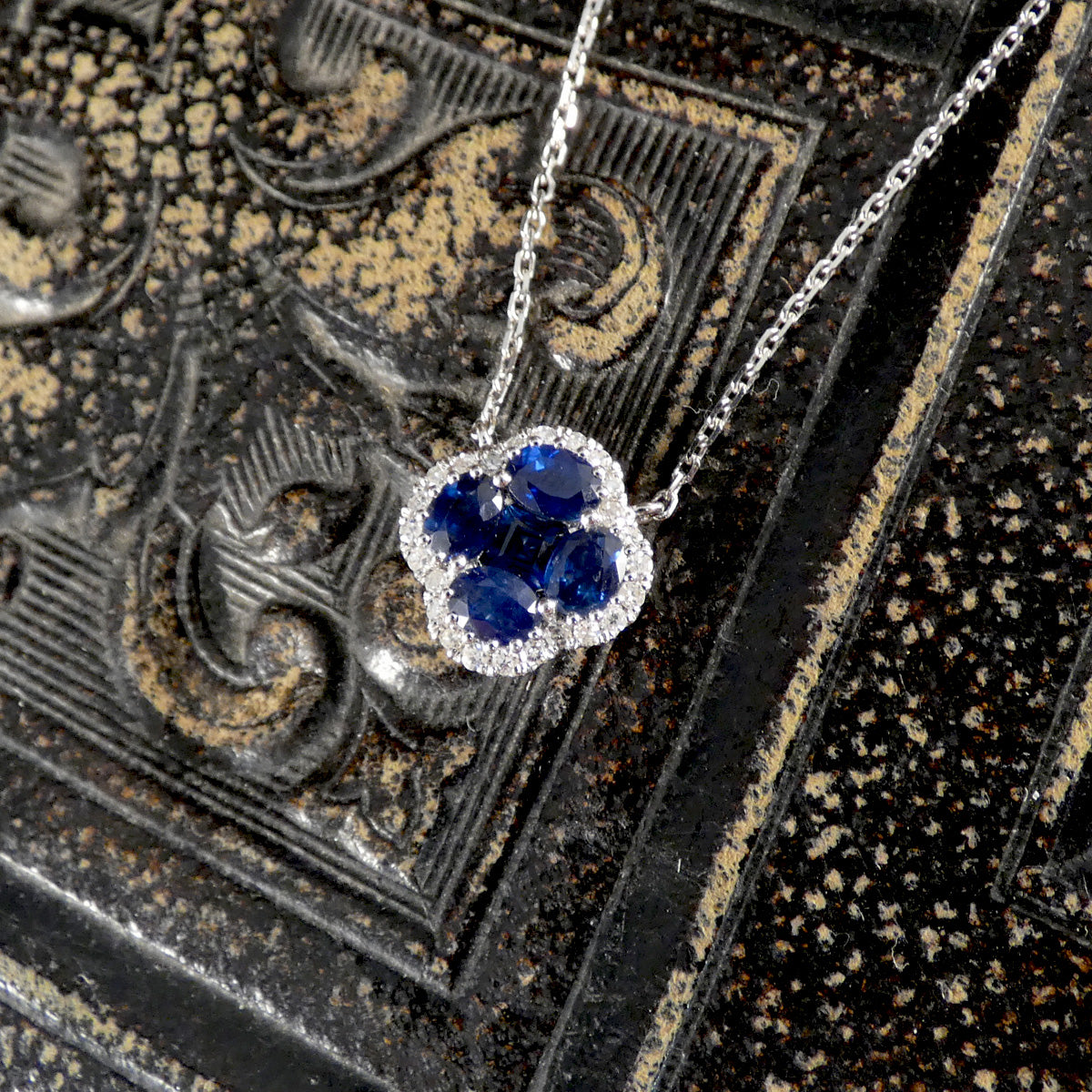 Blue sapphire four leaf clover with a diamond surround attached to a chain necklace 
