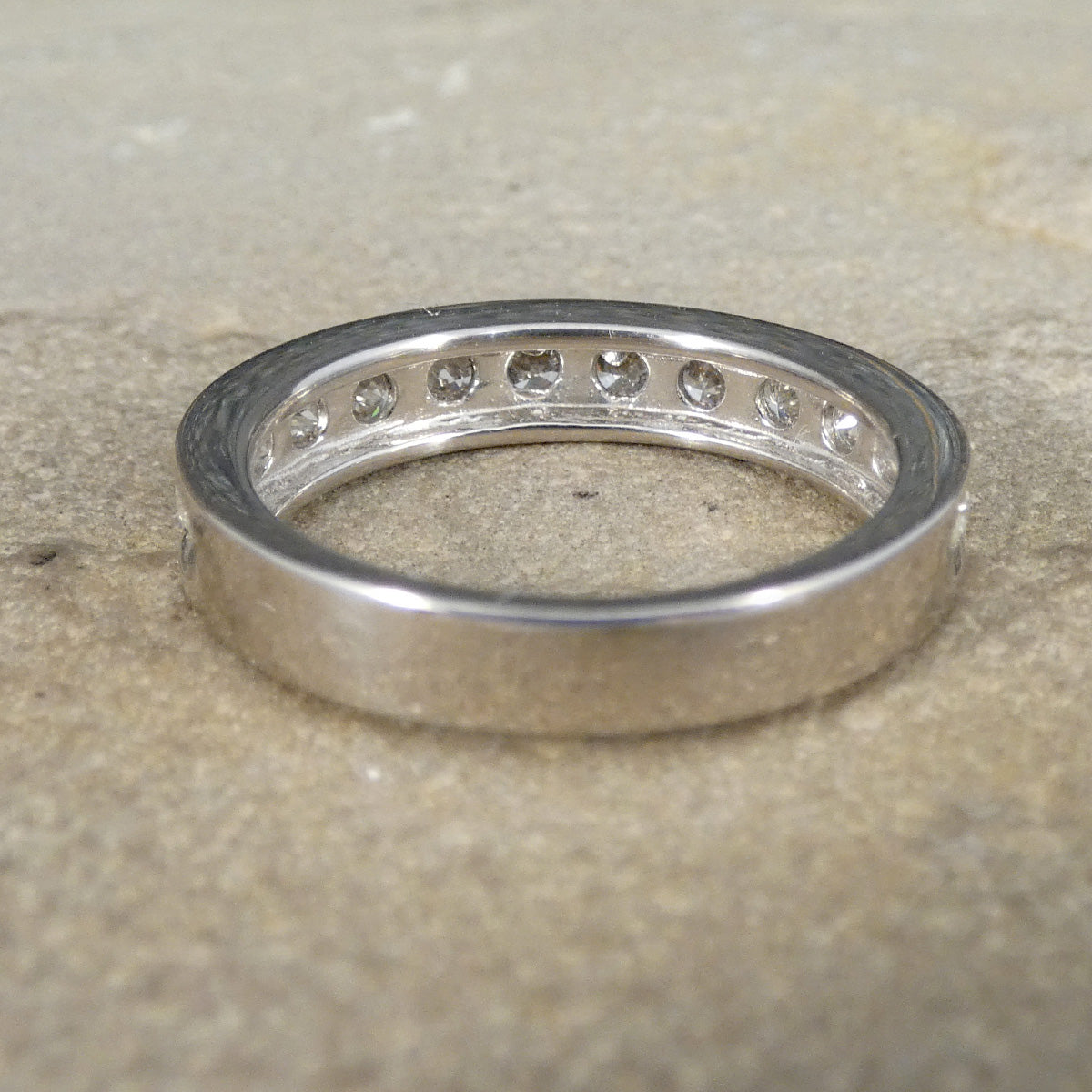Silver ring with embedded stones on a textured beige surface