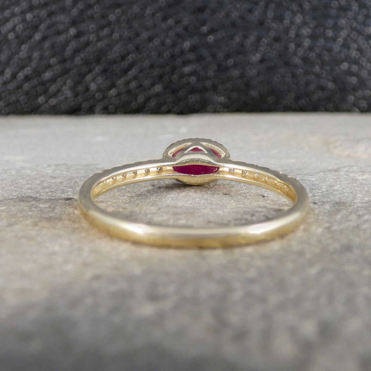 Gold ring with a red gemstone on a textured surface