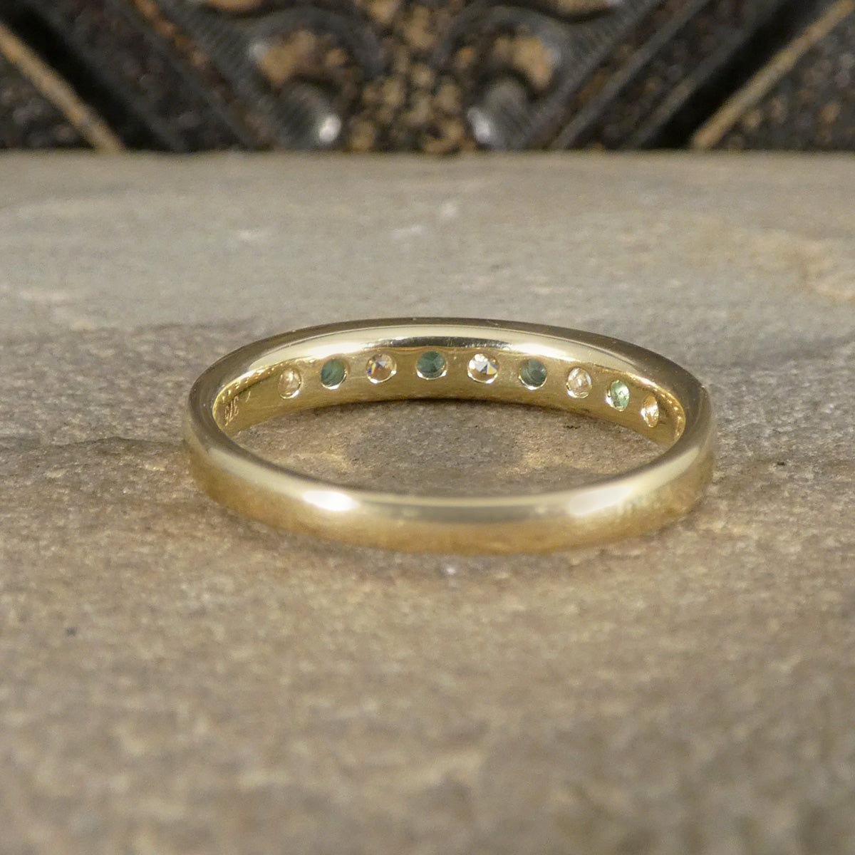 Gold ring with embedded stones on a textured surface