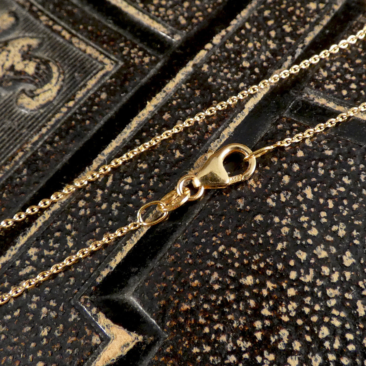 Gold chain with a clasp on an ornate black background