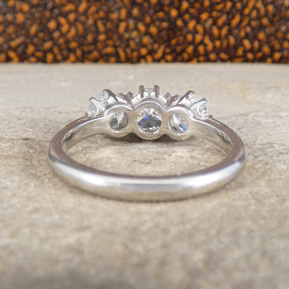 Silver ring with three diamonds on a textured surface