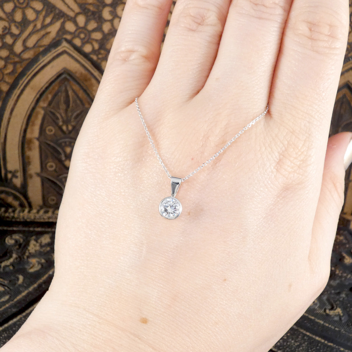A bright and beautiful solitaire diamond pendant necklace with a GIA cert shown on the hand to see size reference. 