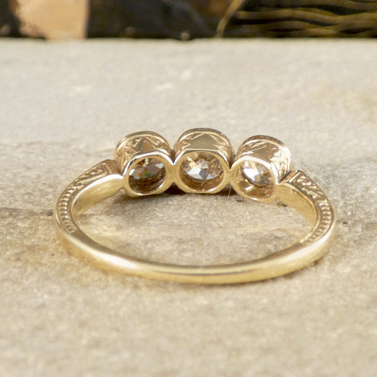 Gold ring with three circular gemstones on a textured surface