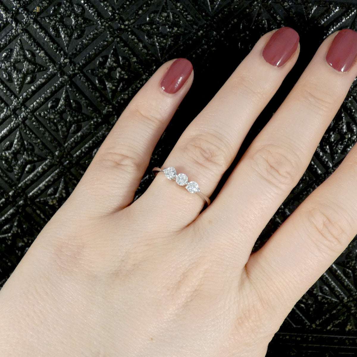 Diamond three stone ring, in a simple setting with a bright and clear appearance. Shown worn on hand for size ratio.