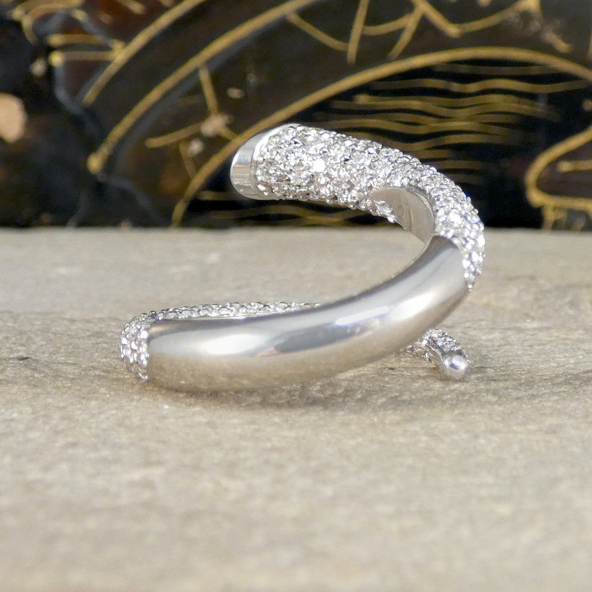 Back view of a unique diamond set snake like ring shown on a stone.