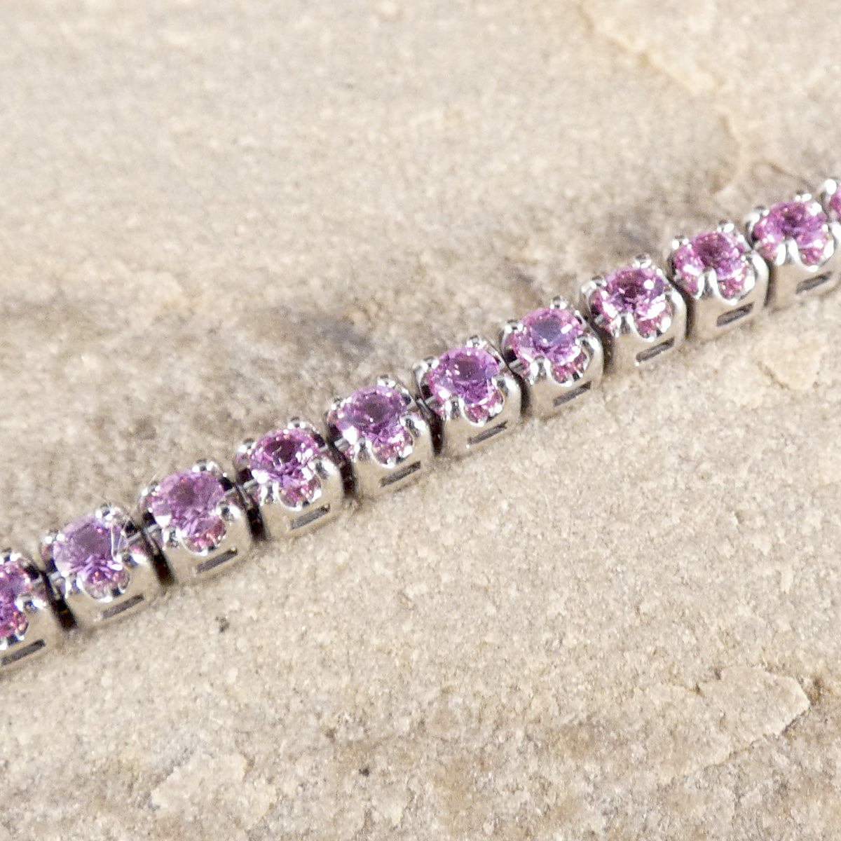 Close up of pink sapphire and diamond tennis bracelet in white gold