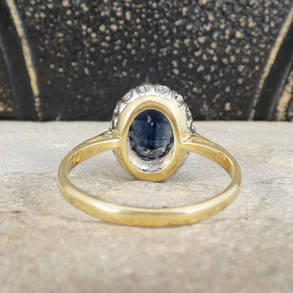 Gold ring with a blue gemstone on a textured surface