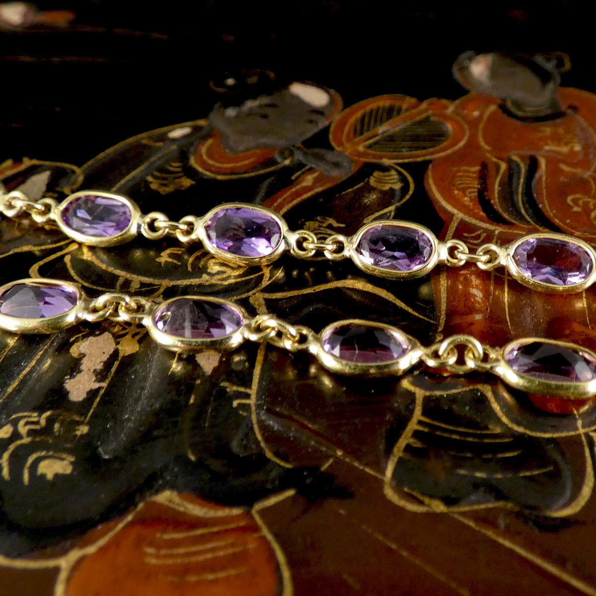 Gold bracelet with purple amethyst gemstones on a decorative background