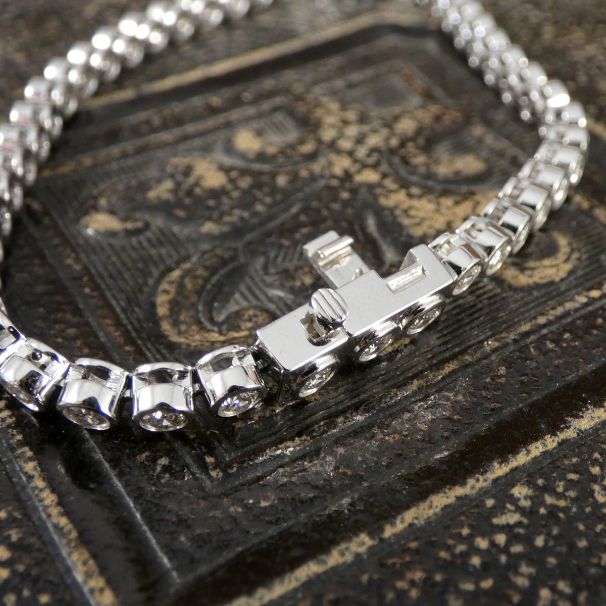 A diamond tennis bracelet in a bezel setting in Platinum showing safety under clasp