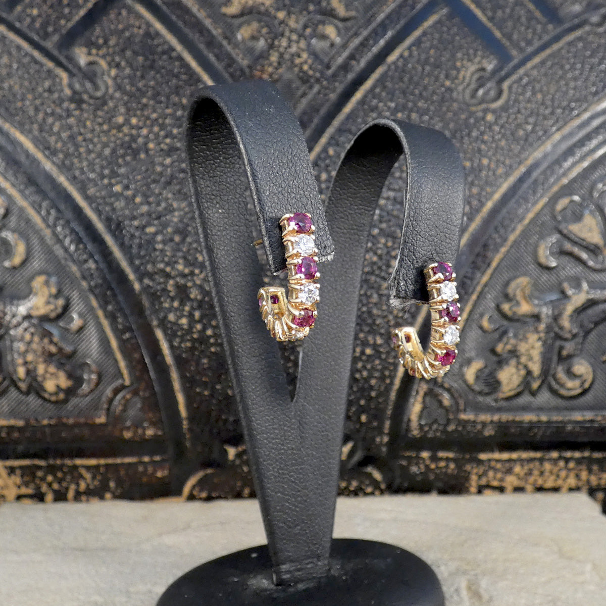 Ruby and Diamond Huggie Earrings in Yellow Gold shown on an earring stand