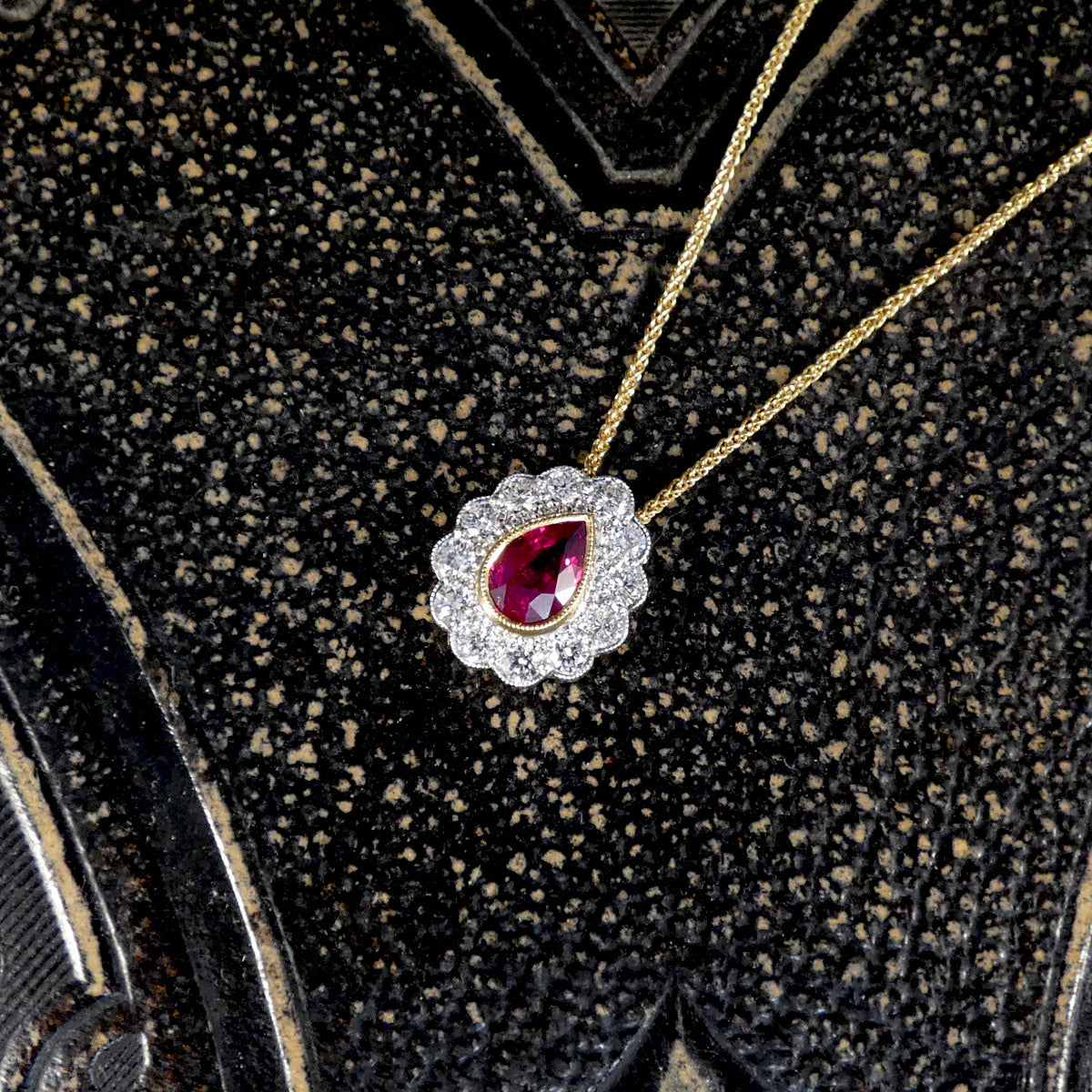 Elegant necklace with a red gemstone pendant on a textured black background