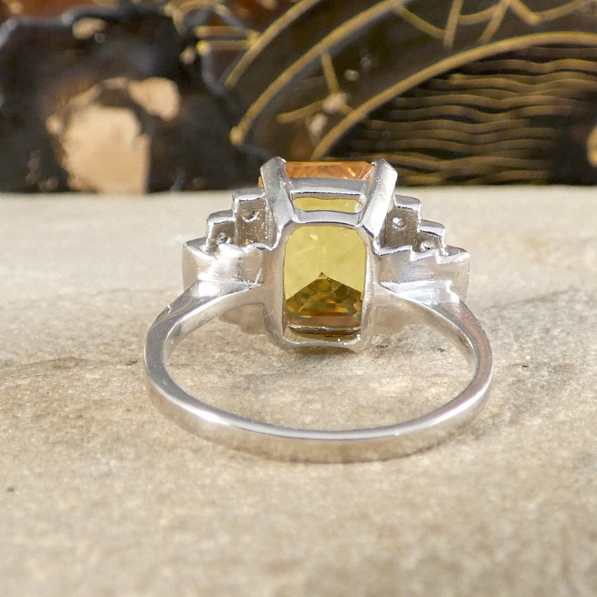 Silver ring with a yellow gemstone on a textured surface