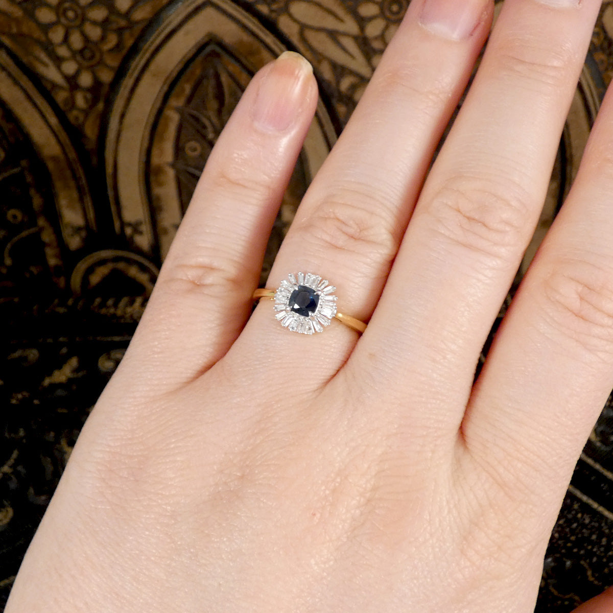 A beautiful blue sapphire and diamond floral cluster ring shown on the finger to see how it looks when worn.