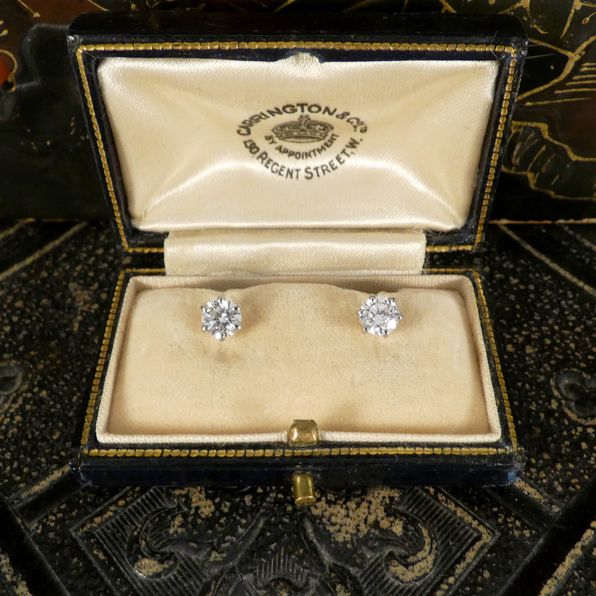 Diamond earrings in a vintage box with a visible brand logo.