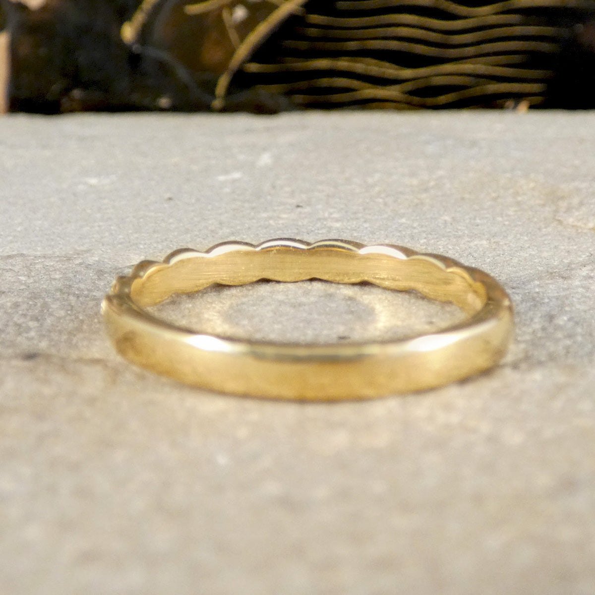 Gold ring with a textured band on a stone surface