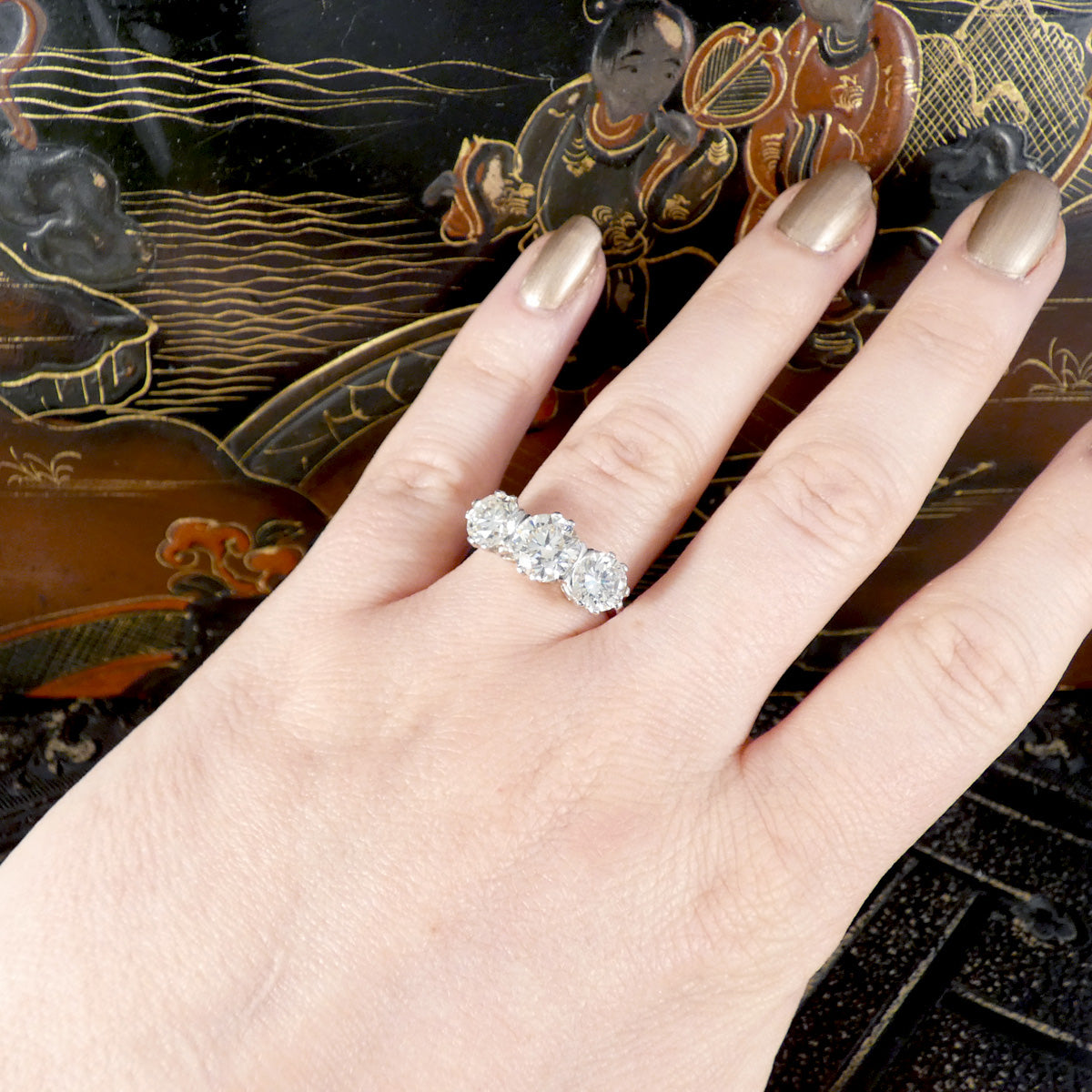A bright and sparkly diamond three stone ring featuring a total of 3.88 carat weight in secure settings in Platinum. Displayed on the hand to see size and colour reference.