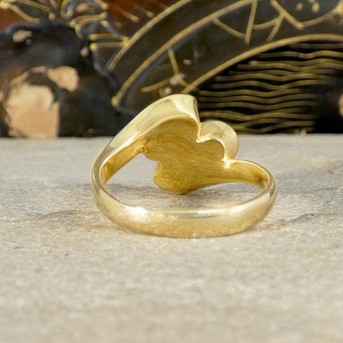 Gold ring with a unique design on a textured surface