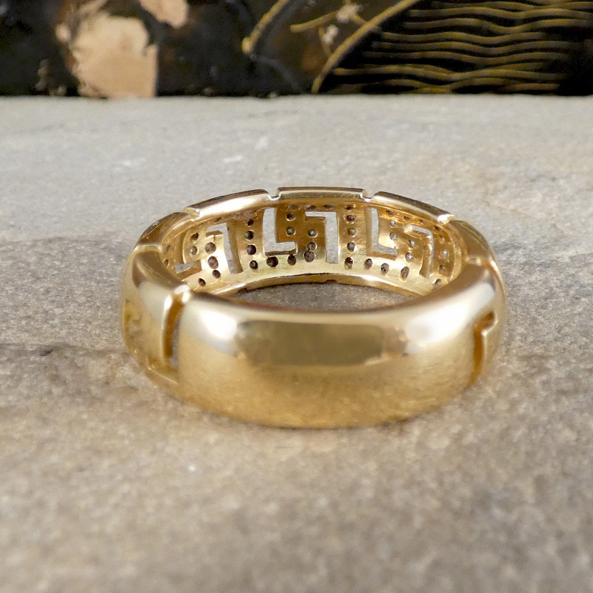 Gold ring with intricate design on a textured surface