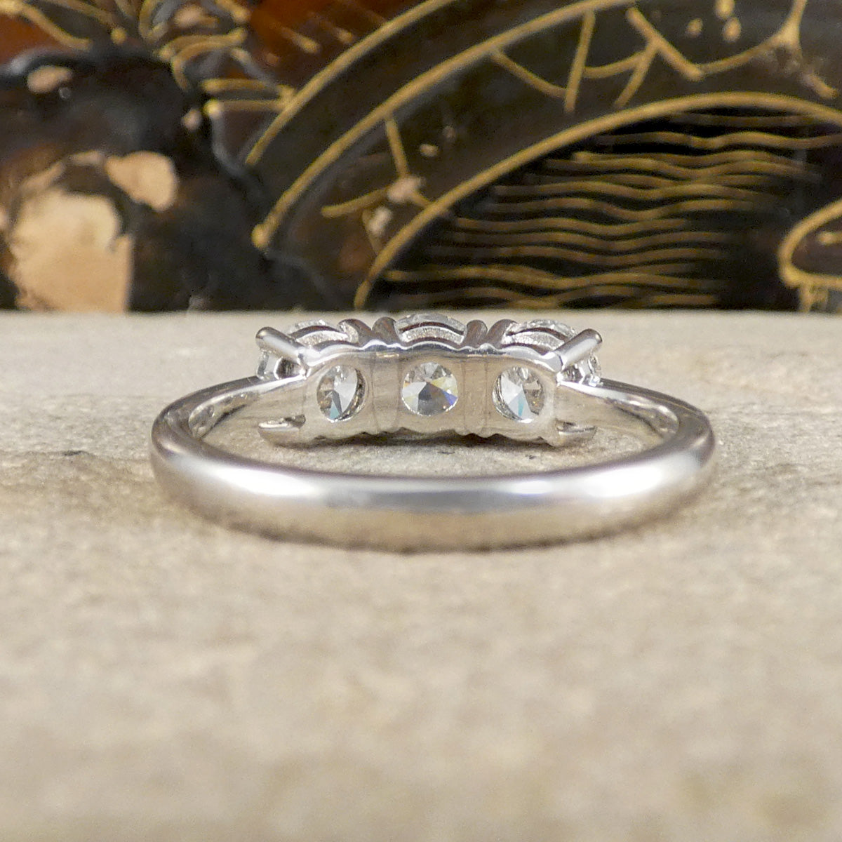 Platinum ring with three diamonds on a textured surface