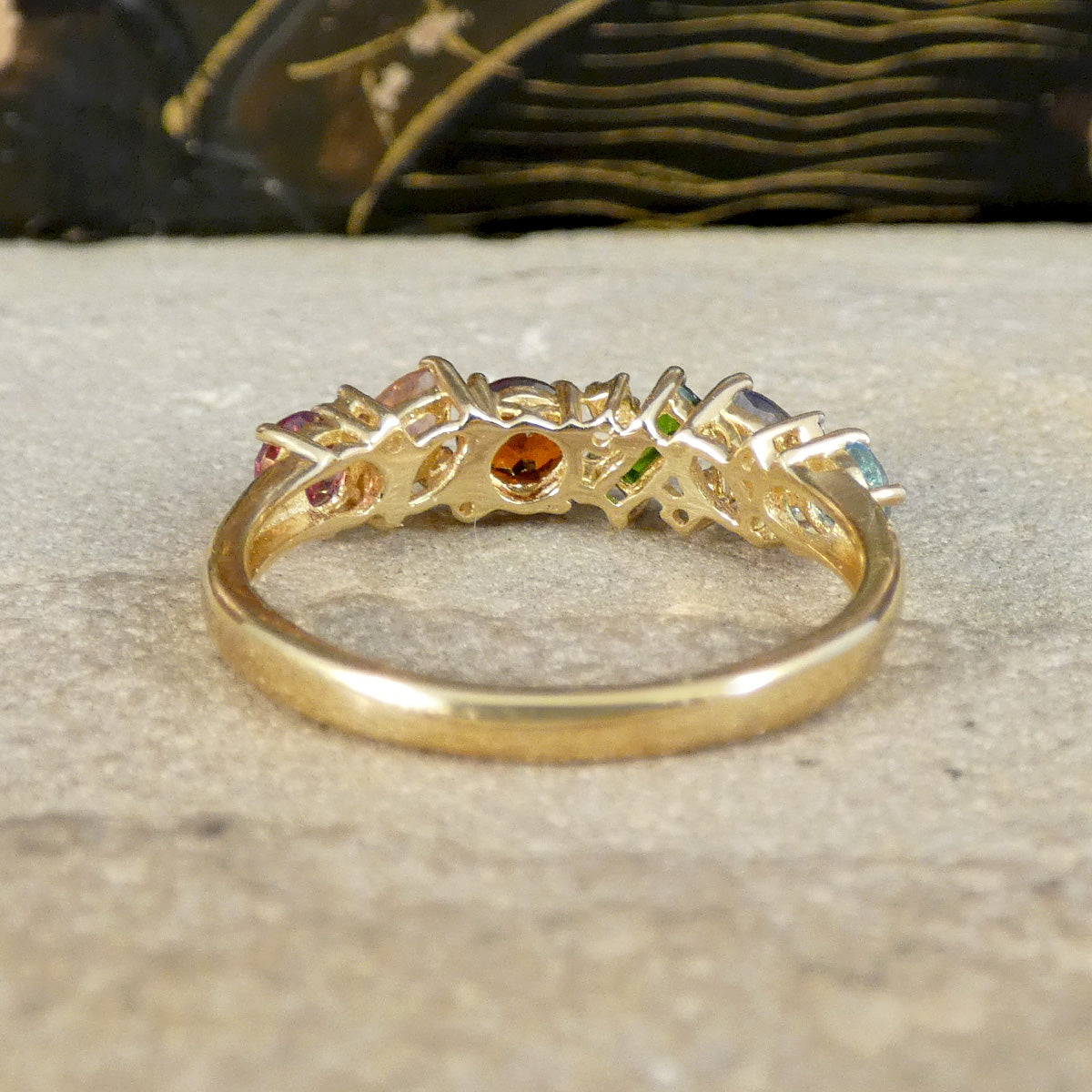 Gold ring with embedded gemstones on a textured surface