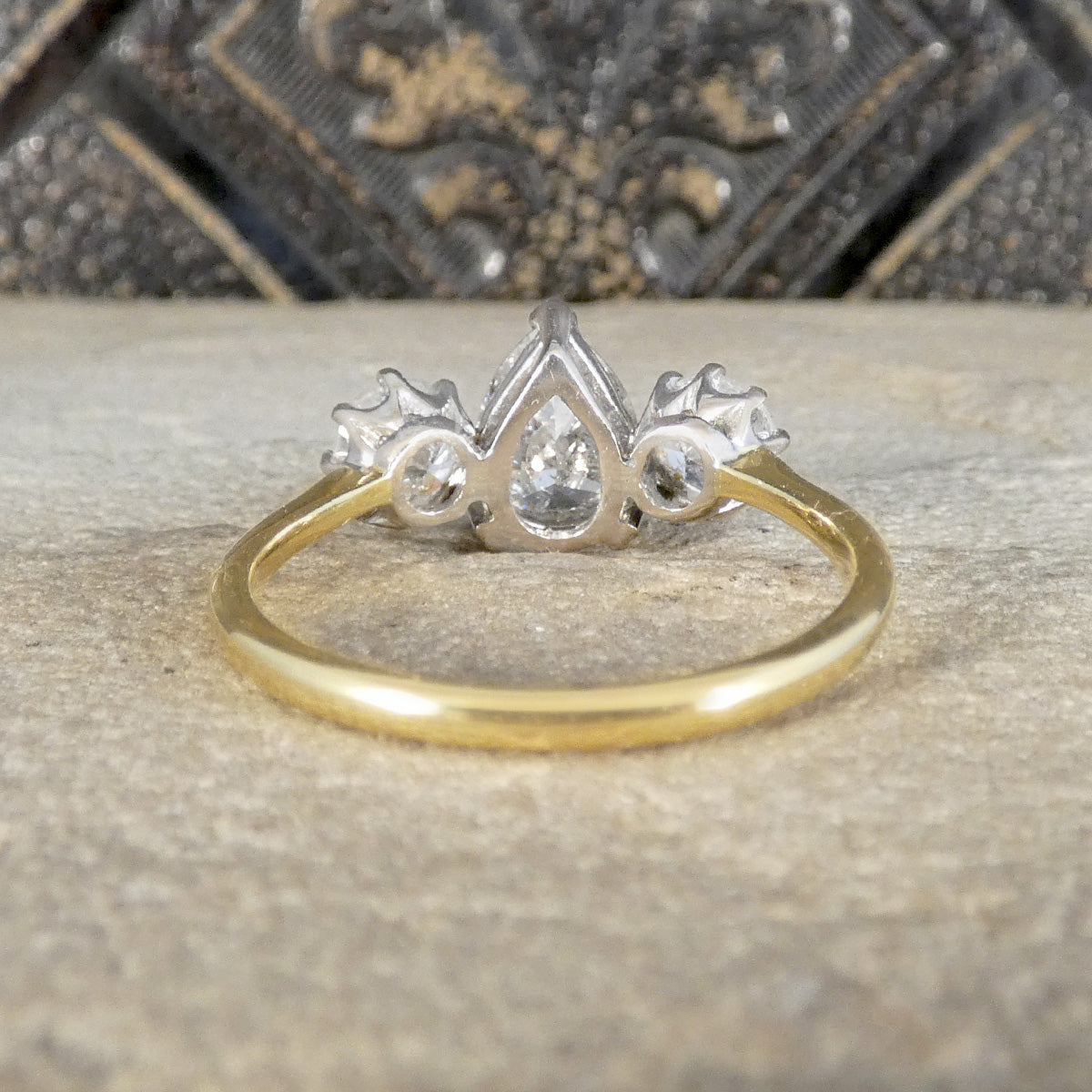 Gold ring with a diamond-shaped center and smaller diamonds on a textured surface