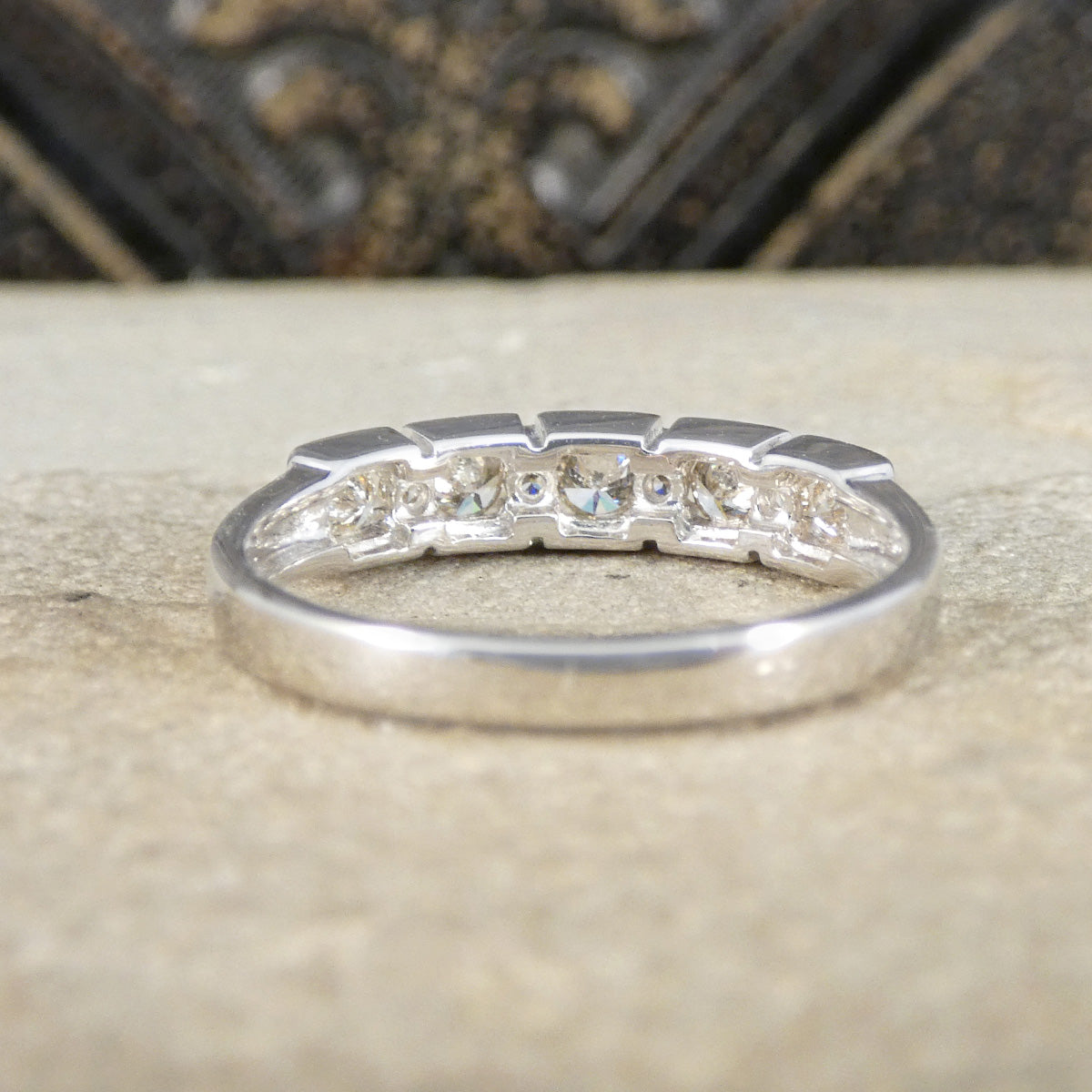 Silver ring with embedded diamonds on a textured surface