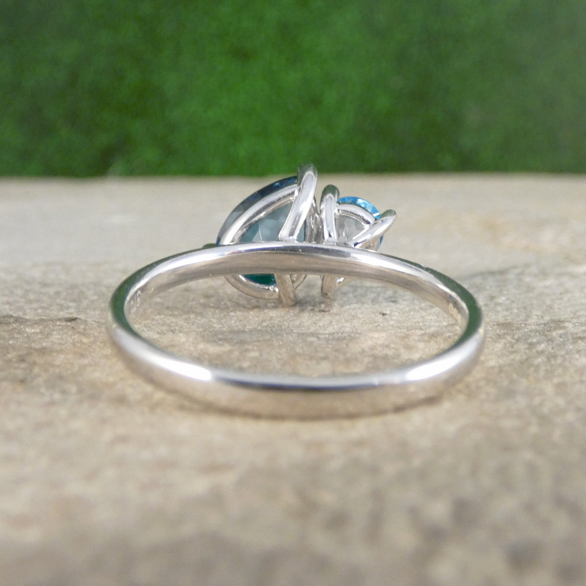 Silver ring with a blue gemstone on a textured surface with a green background