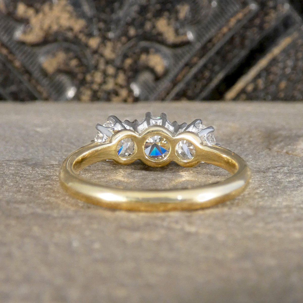 Gold ring with three diamond gemstones on a textured surface