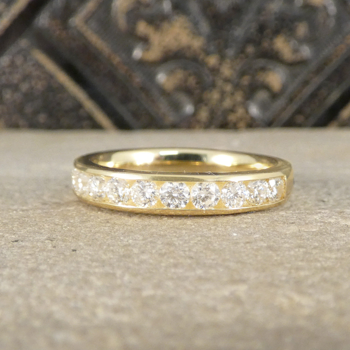 Gold ring with embedded diamonds on a textured surface